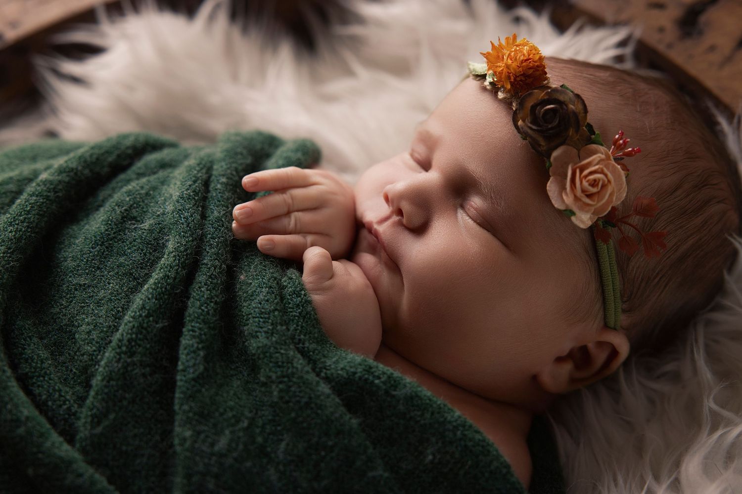A sleeping baby wearing an orange floral headband rests peacefully on white fur in a series of close-up portraits.