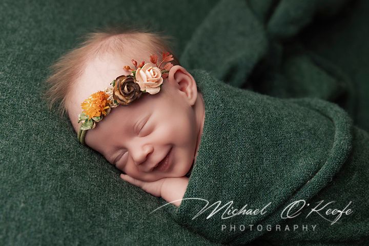 A series of artistic newborn baby photos arranged in a horizontal strip against a dark green textured backdrop.