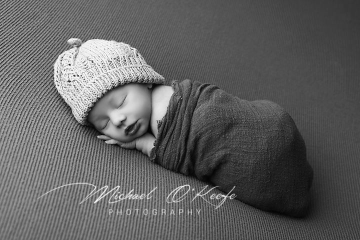 A series of black and white newborn photography images showing a sleeping baby wrapped in cozy blankets.