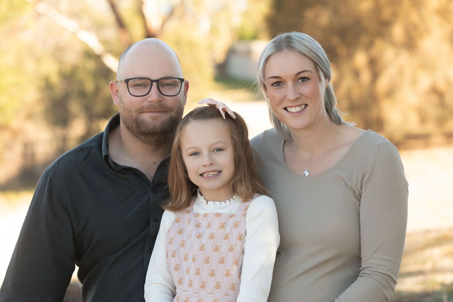 Outdoor family photoshoot featuring casual attire and natural interactions in golden sunlight.
