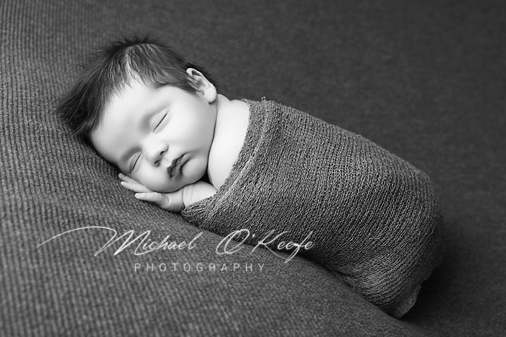 Black and white newborn photography series showing sleeping baby wrapped in soft fabric in various peaceful poses.
