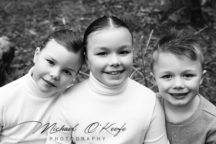 Black and white portrait of children smiling and laughing together outdoors.