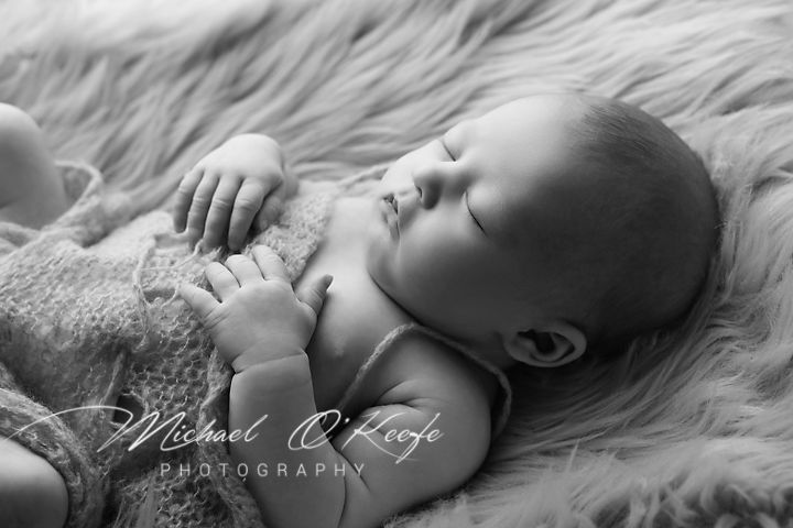 Black and white portrait series showing newborn baby details and poses on soft textures.