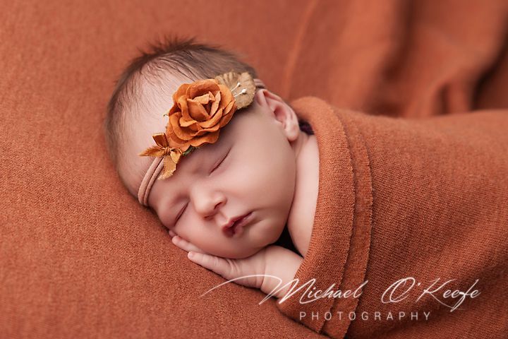 Professional newborn photography series with baby on terracotta backdrop and floral details.