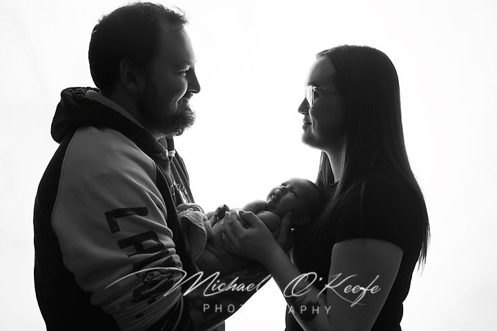 Black and white photo of couple tenderly holding newborn baby, captured by Michael O'Keefe Photography.