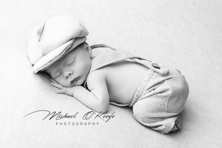 Black and white artistic photo series showing sleeping newborn baby in soft white wraps and blankets.