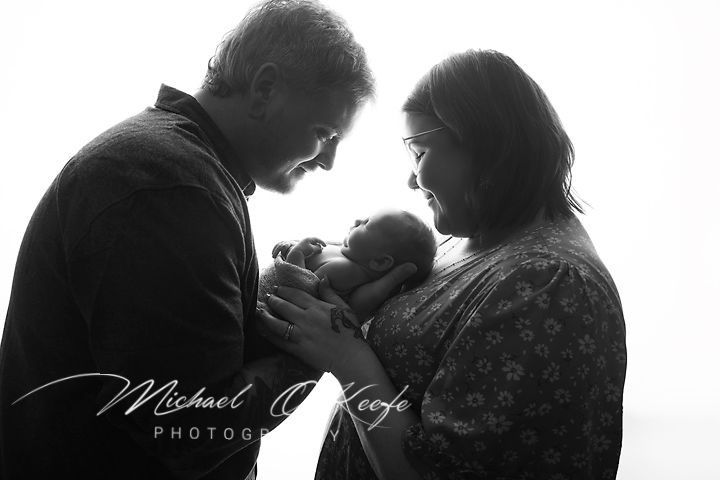 Black and white photo of parents tenderly holding their newborn baby, captured by Michael O'Keefe Photography.