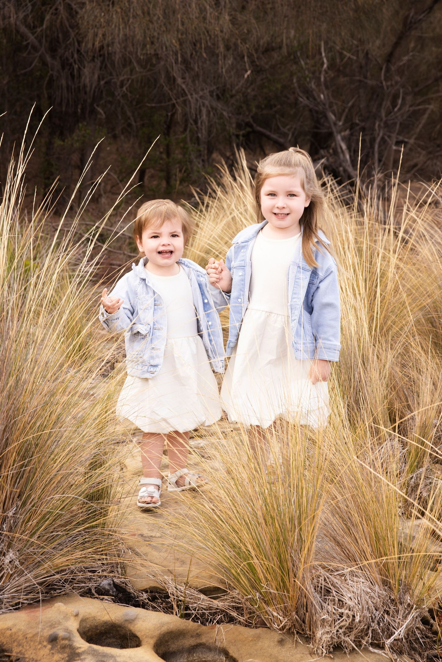 Children sit among tall ornamental grasses during an outdoor photo session.