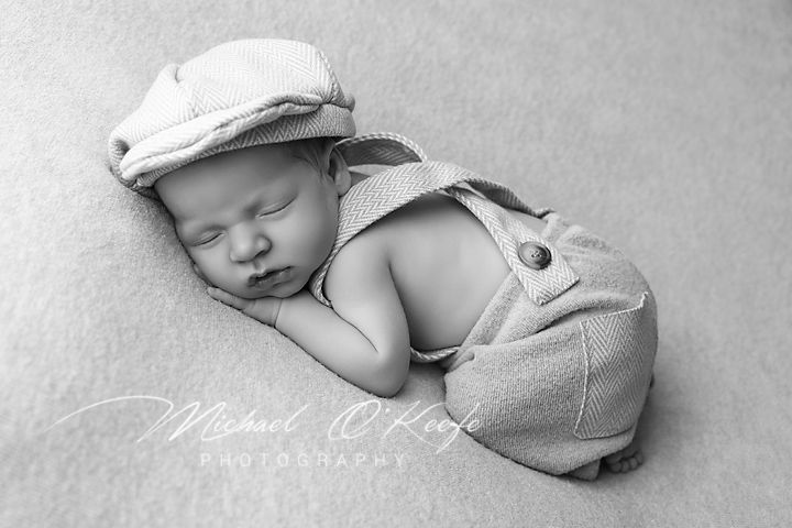 Black and white collage of a sleeping infant with soft knit booties and blanket details.