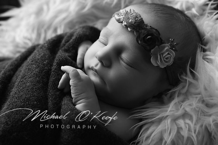 Black and white newborn portrait of sleeping baby with floral headband by Michael O'Keefe Photography.