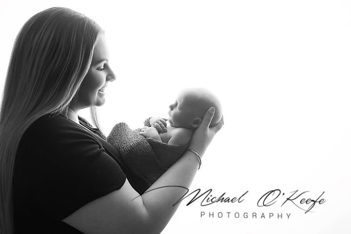 Black and white photo of a mother tenderly holding her newborn baby, captured by Michael O'Keefe Photography.