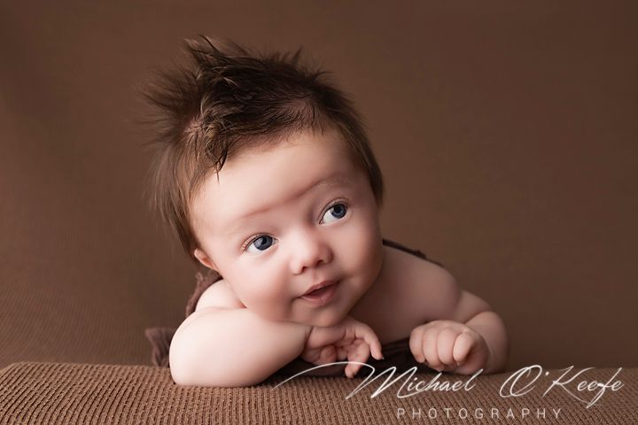 A series of sepia-toned portraits of a baby showing different expressions and poses against a brown backdrop.