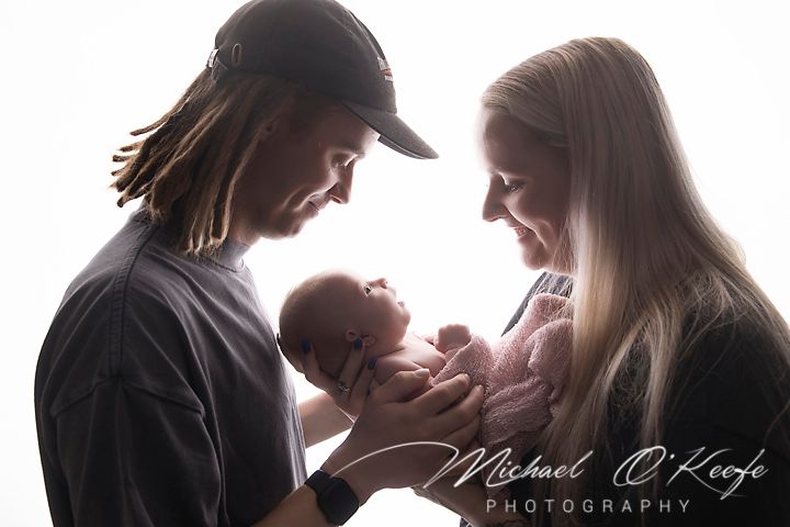 A black and white photo collage shows tender moments between parents and their newborn baby in various poses.