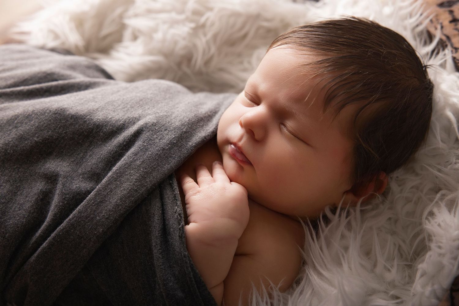 A sleeping baby lies peacefully on soft white bedding in a series of gentle poses.
