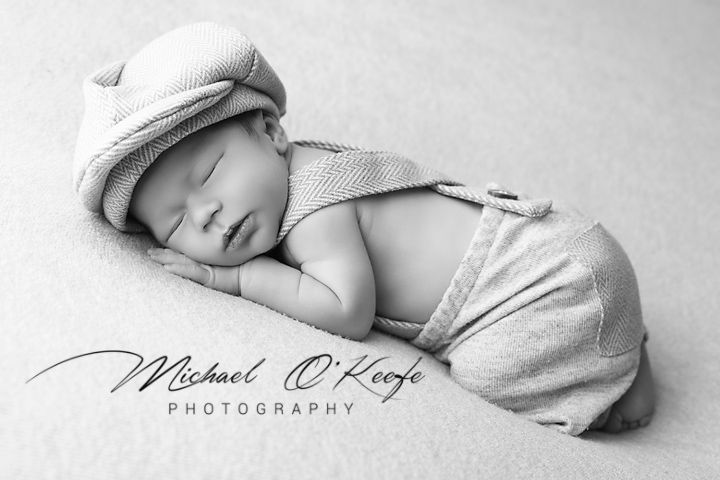 Black and white panoramic series of newborn baby sleeping peacefully in soft wraps and blankets.