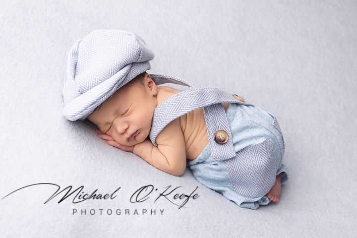 Newborn studio photography series featuring baby in soft blue wraps and blankets on white backgrounds.