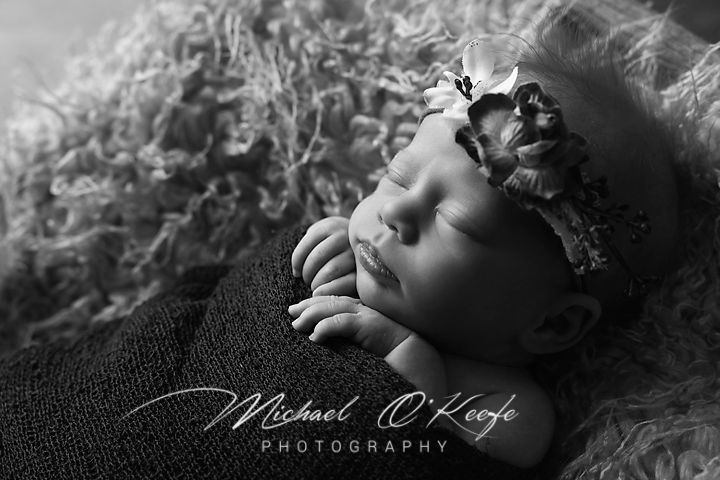 Black and white artistic portrait showing a person lying down with curly hair in soft lighting.