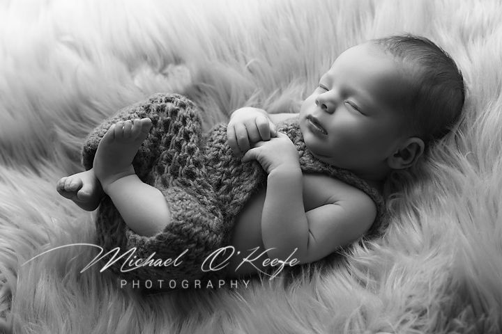 A collection of black and white newborn photography portraits showing a sleeping baby on soft white fur.