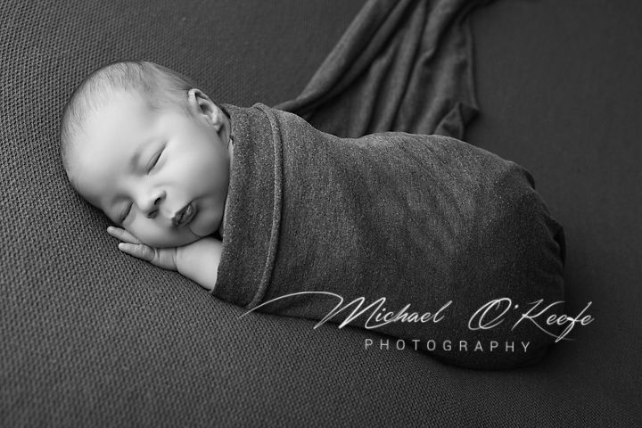 Black and white newborn photo of sleeping swaddled baby by Michael O'Keefe Photography.