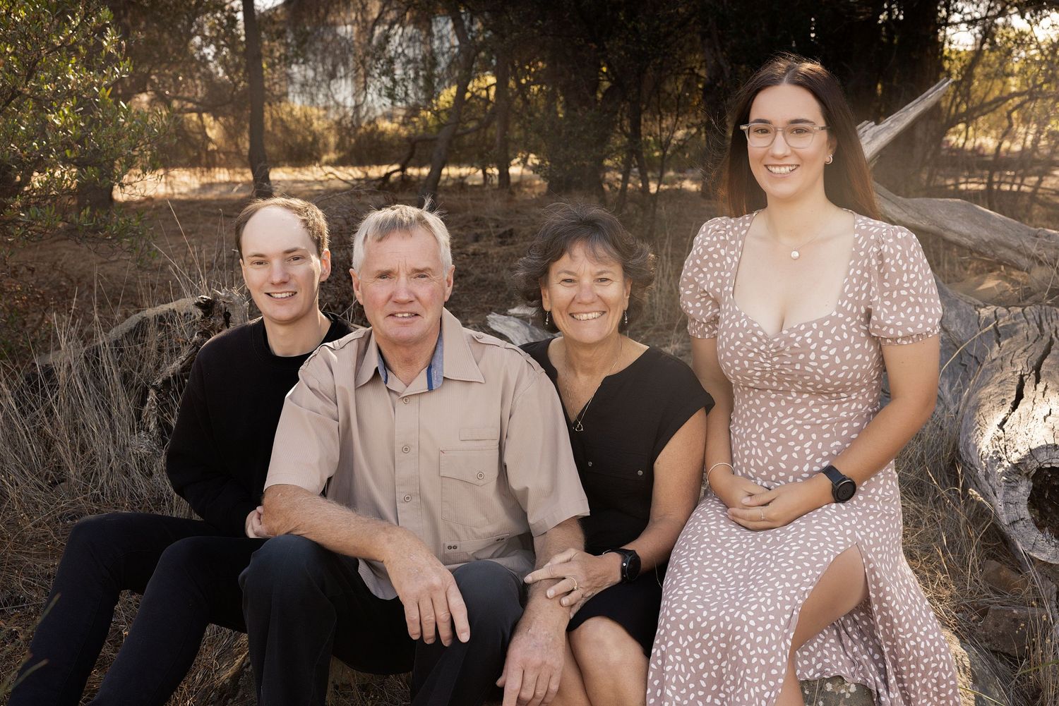 Family members gather together for photos in a natural outdoor setting with trees.