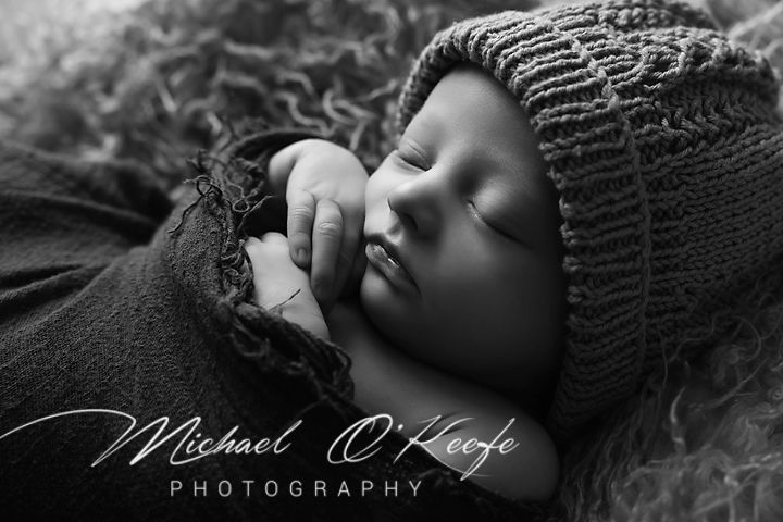 Black and white artistic newborn photography series showing peaceful sleeping baby wrapped in soft knit blankets.