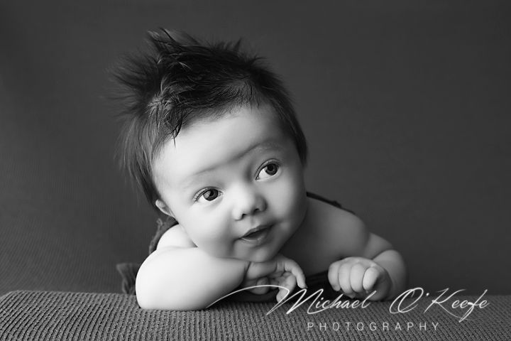 Black and white photo series showing close-up portraits of a baby with expressive faces and poses.