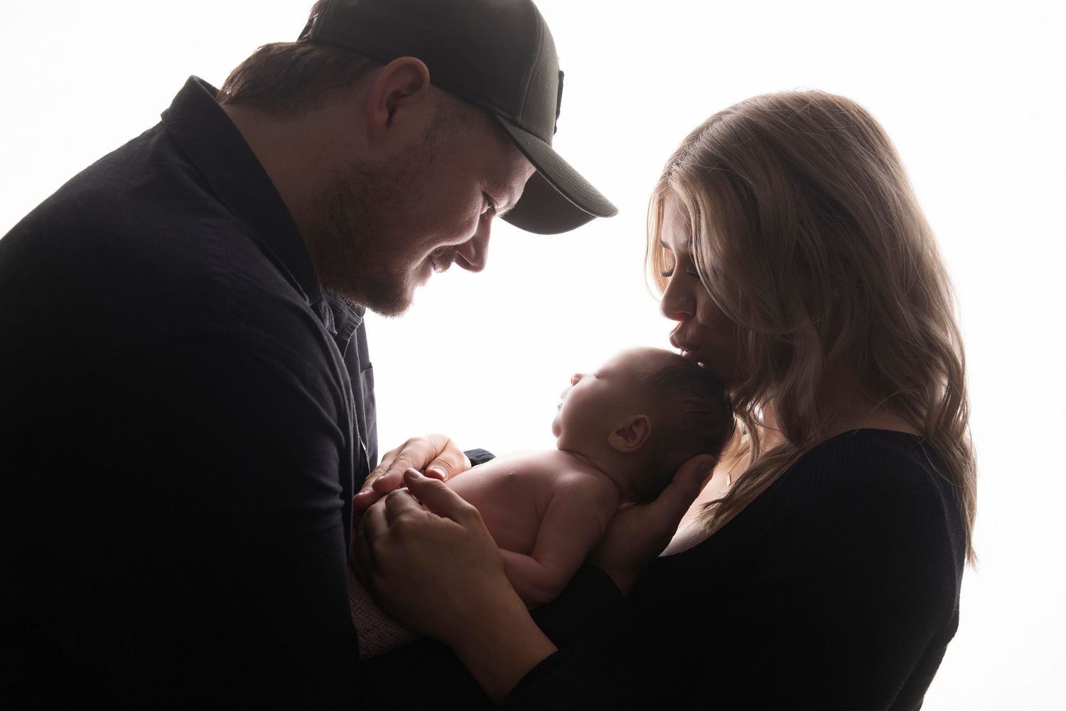 Family silhouette portrait showing tender moment with newborn baby.