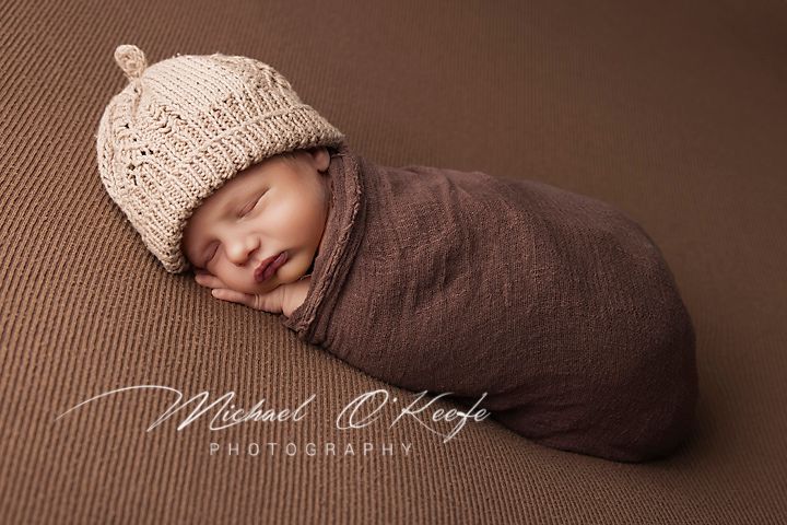 A series of sepia-toned newborn photography shots showing a sleeping baby wrapped in brown fabric.