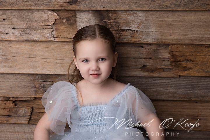 Three portraits taken against a rustic wood wall with different expressions and lighting effects.