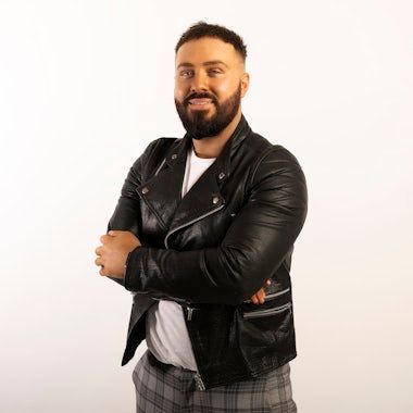 Person in black leather jacket poses confidently against white background.