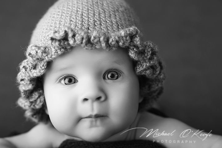 Black and white portrait of an adorable baby wearing a crocheted hat, photographed by Michael O'Keefe Photography.