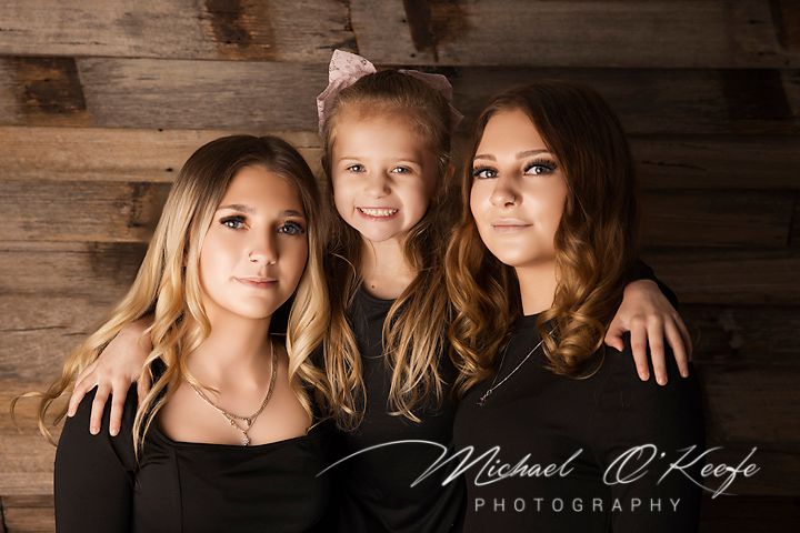 Professional senior portrait photo session against rustic wooden wall background in natural lighting.