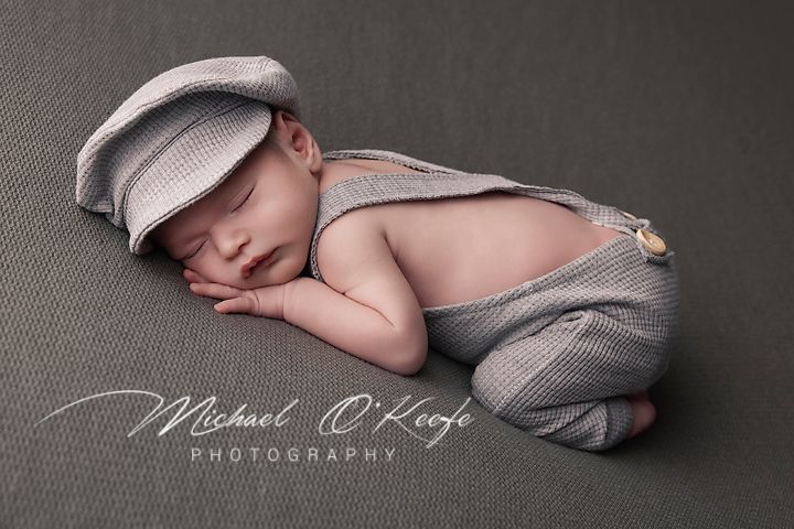 A series of soft black and white newborn photography portraits showing a sleeping baby in gentle poses with gray fabric.
