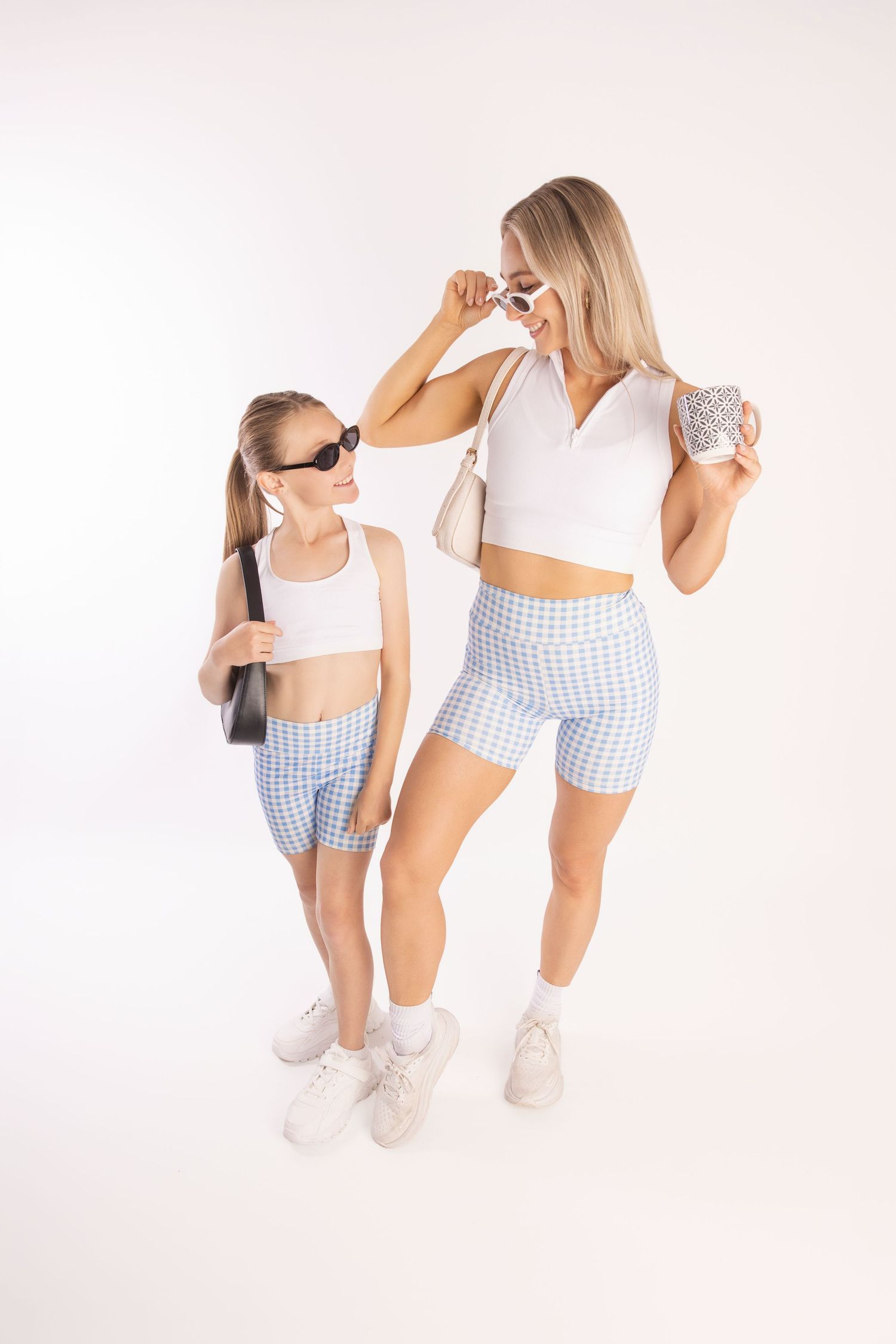 Two people in coordinating athletic wear and sunglasses pose against a white studio backdrop.