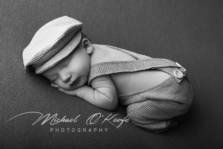 A collection of black and white artistic newborn photography portraits showing a sleeping baby in soft poses and textures.