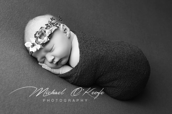 Black and white newborn photography collage showing sleeping baby in various wrapped and curled poses.