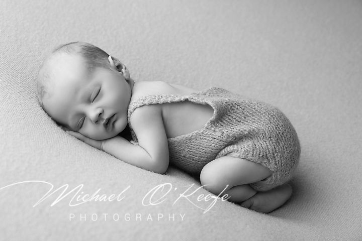 A series of black and white newborn photography images showing a sleeping baby in soft lighting and poses.