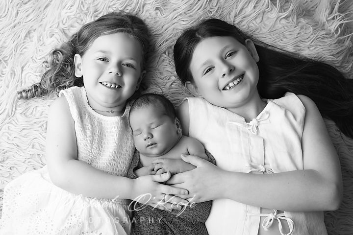 Black and white photo series showing siblings laughing and playing together while lying down.