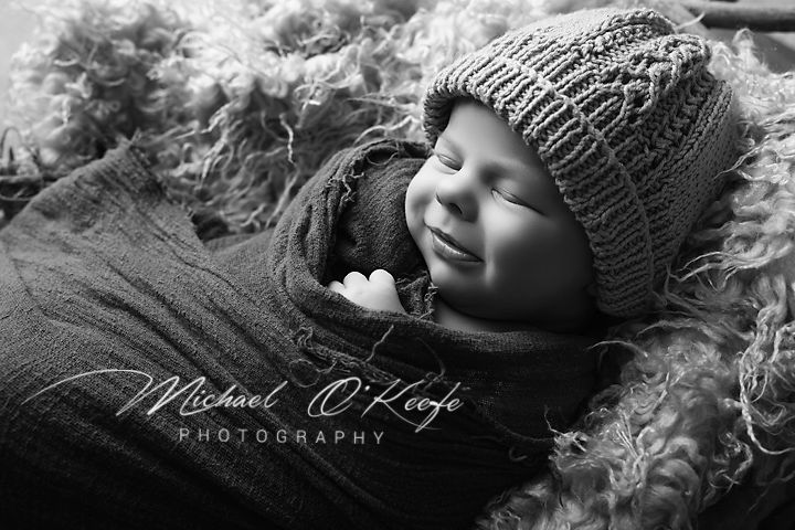 Black and white newborn portrait of a sleeping baby in a knit hat, by Michael O'Keefe Photography.