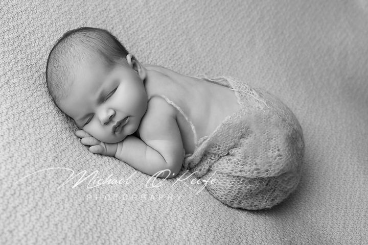 An artistic black and white photo series showing a sleeping newborn baby in different poses on a textured surface.