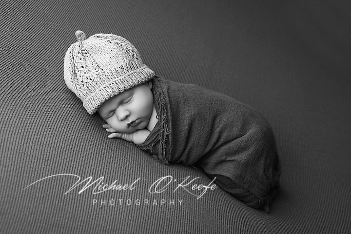 High contrast black and white portrait of sleeping newborn in soft wrap.
