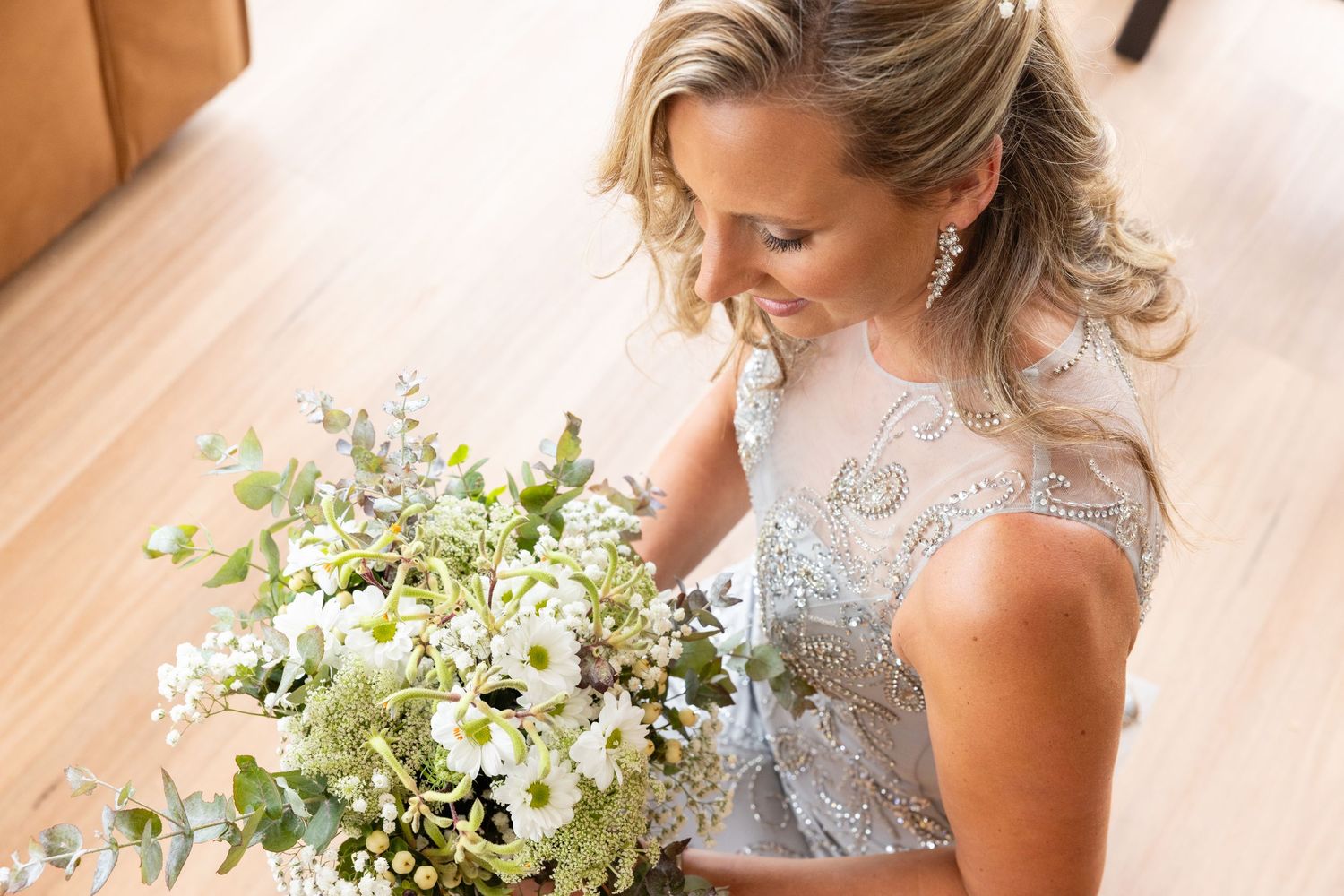 Bridal portrait showing woman holding white and blue floral bouquet in lace dress.