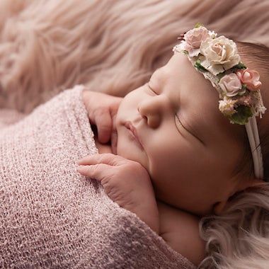 Dreamy newborn portrait with pink tones and delicate floral headpiece.