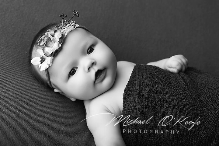 Adorable newborn baby in black and white portrait wearing a floral crown headband.