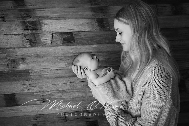 Black and white photo of a mother tenderly holding her newborn baby, captured by Michael OKeefe Photography.