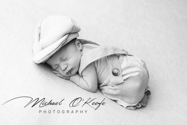 A peaceful black and white collage of sleeping newborn baby images wrapped in soft blankets.