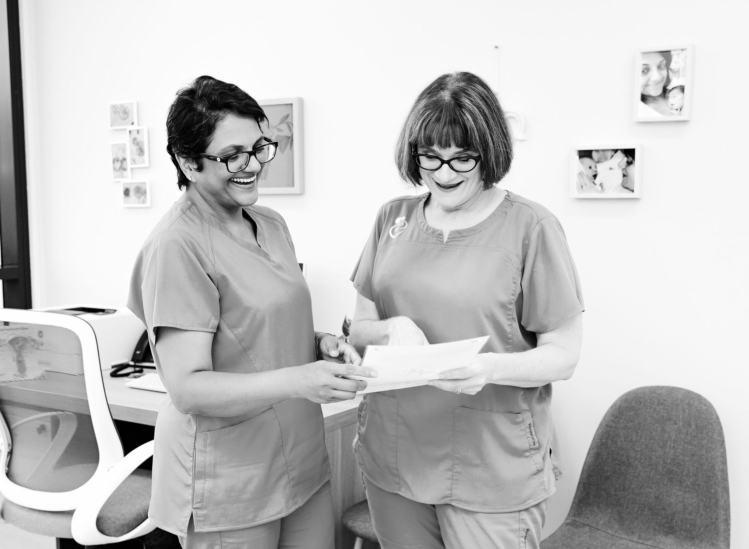 Healthcare professionals review medical documents together while standing at a counter in a clinical setting.