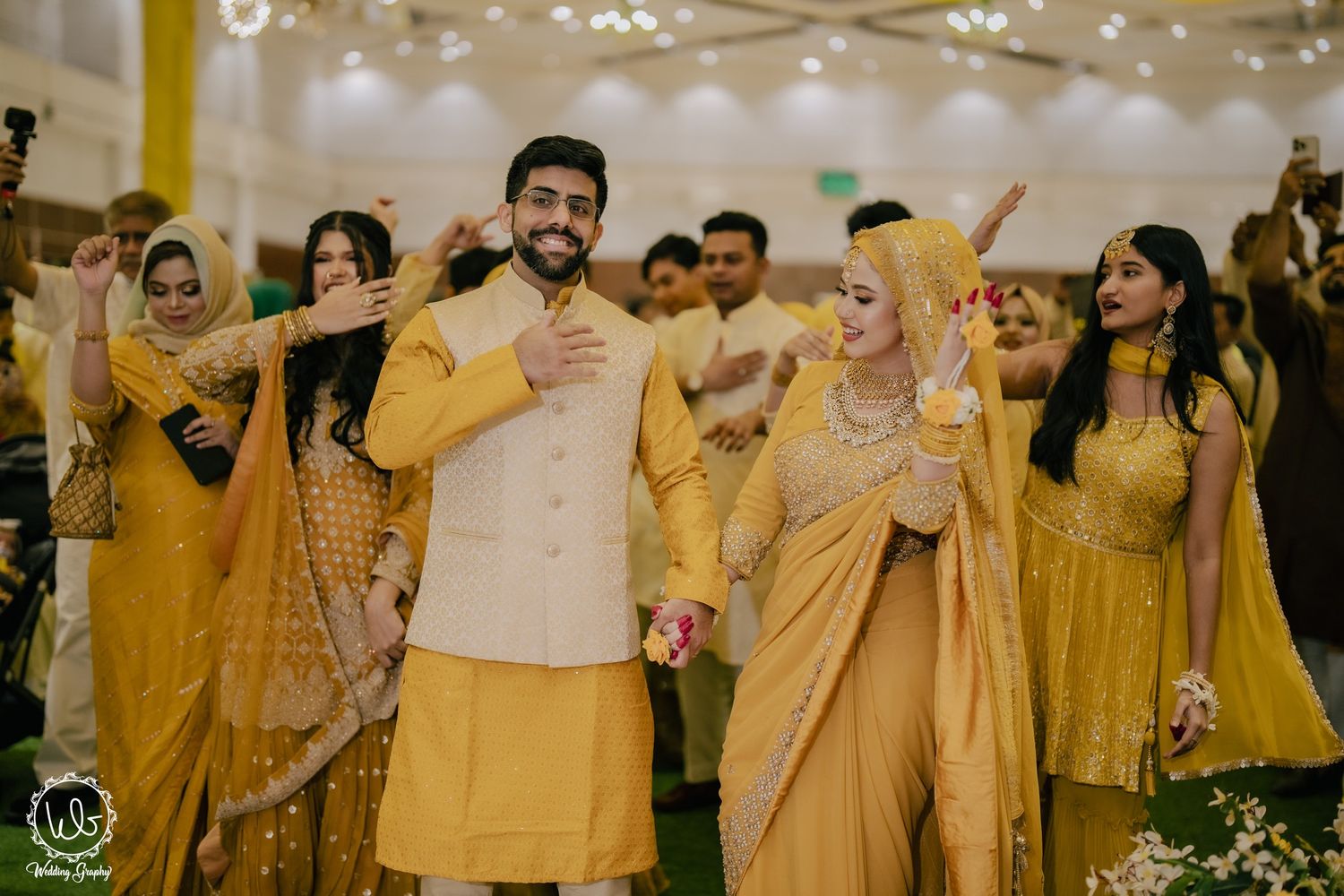 Wedding celebration with guests dancing in coordinated yellow and gold traditional outfits.