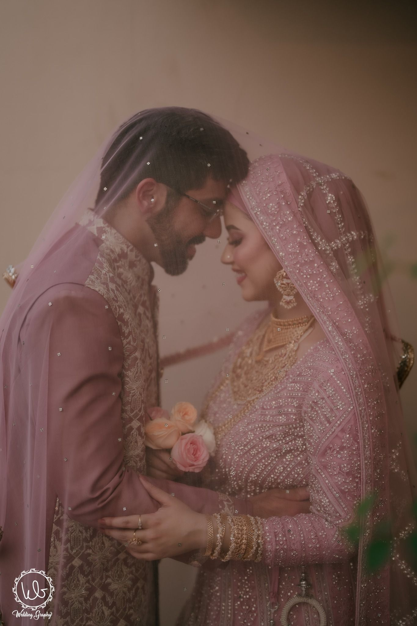 A romantic couple in traditional pink and gold South Asian wedding attire share intimate moments in a photo series.