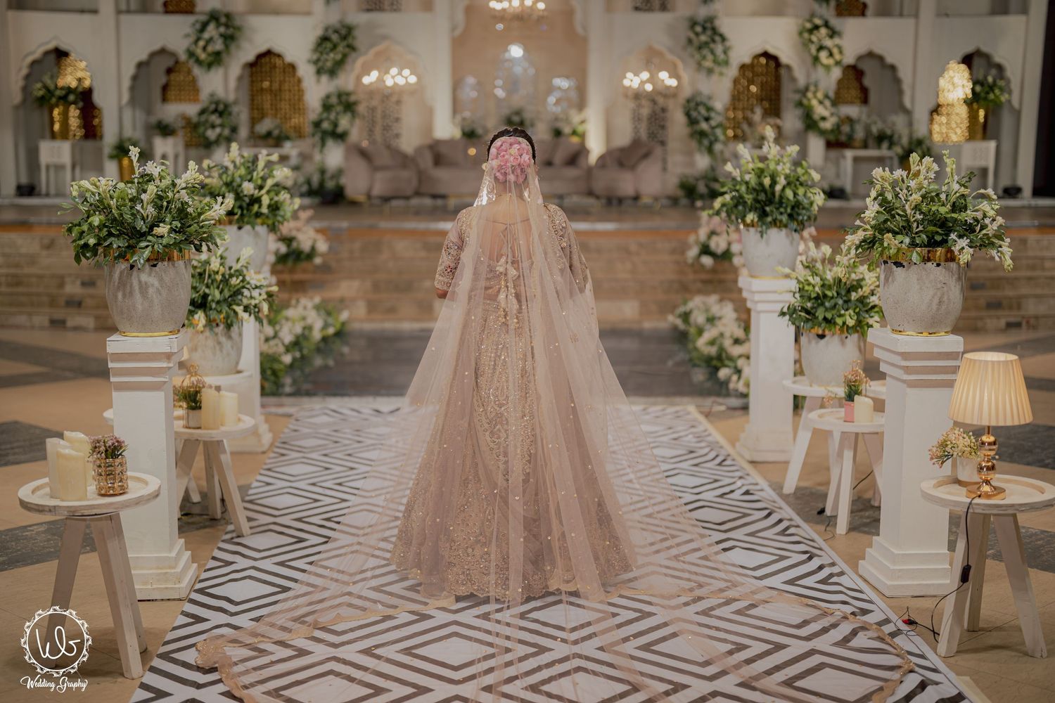 A luxurious wedding venue decorated with floral arrangements and geometric floor patterns creates an elegant atmosphere.